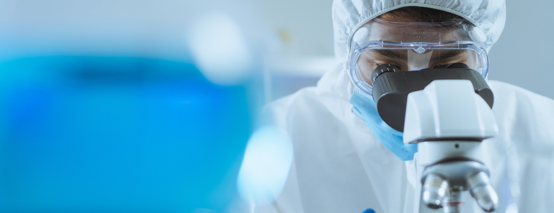Technicien en combinaison stérile examinant un échantillon au microscope dans un laboratoire modulaire Kum Concept