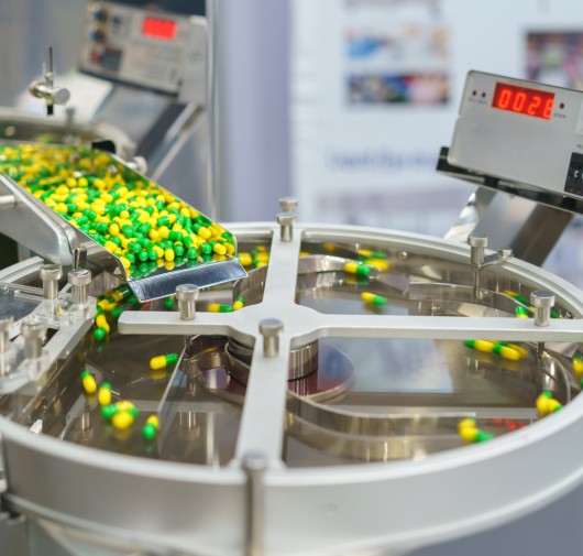 Contrôle qualité de production pharmaceutique : gélules inspectées sur ligne d'équipement de laboratoire modulaire Kum Concept